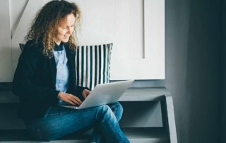 chica sentada en piso con portatil Habitaciones para universitarios UNIHABIT