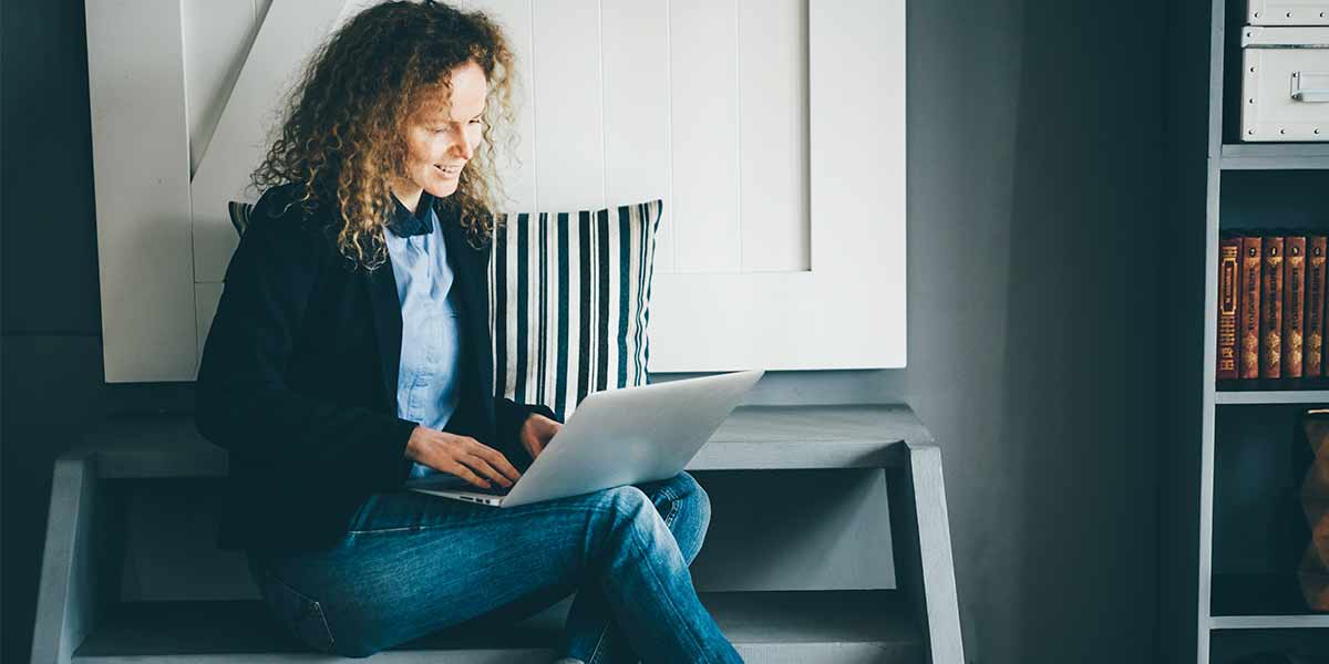 chica sentada en piso con portatil Habitaciones para universitarios UNIHABIT