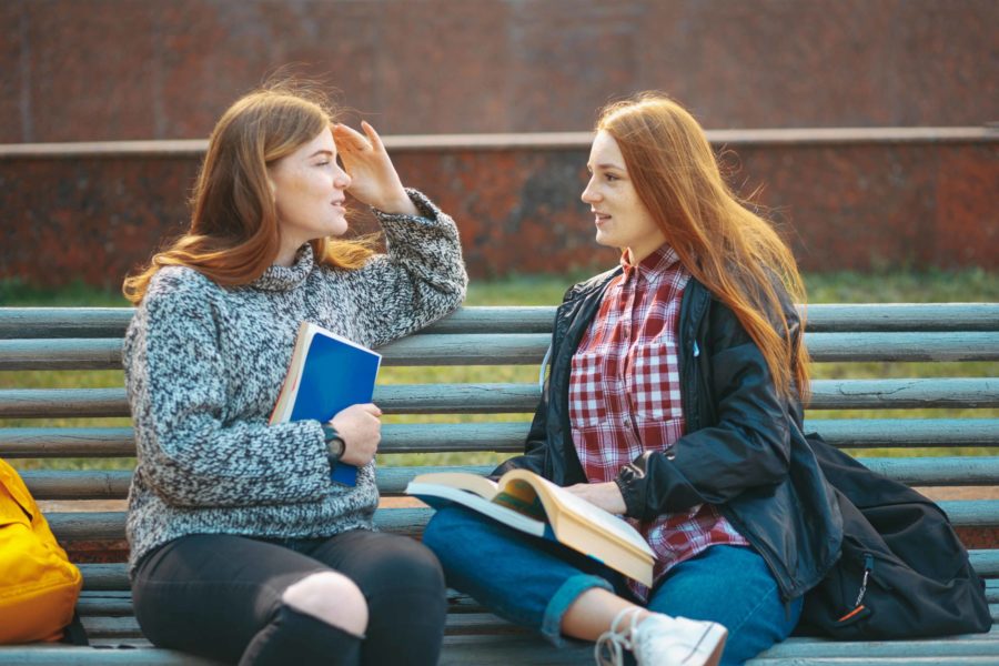 dos chicas hablando en banco Aprender un nuevo idioma en Barcelona Unihabit scaled 900x600 1